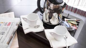 Una bandeja con una cafetera, dos tazas, una cuchara y un periódico sobre una mesa de madera.