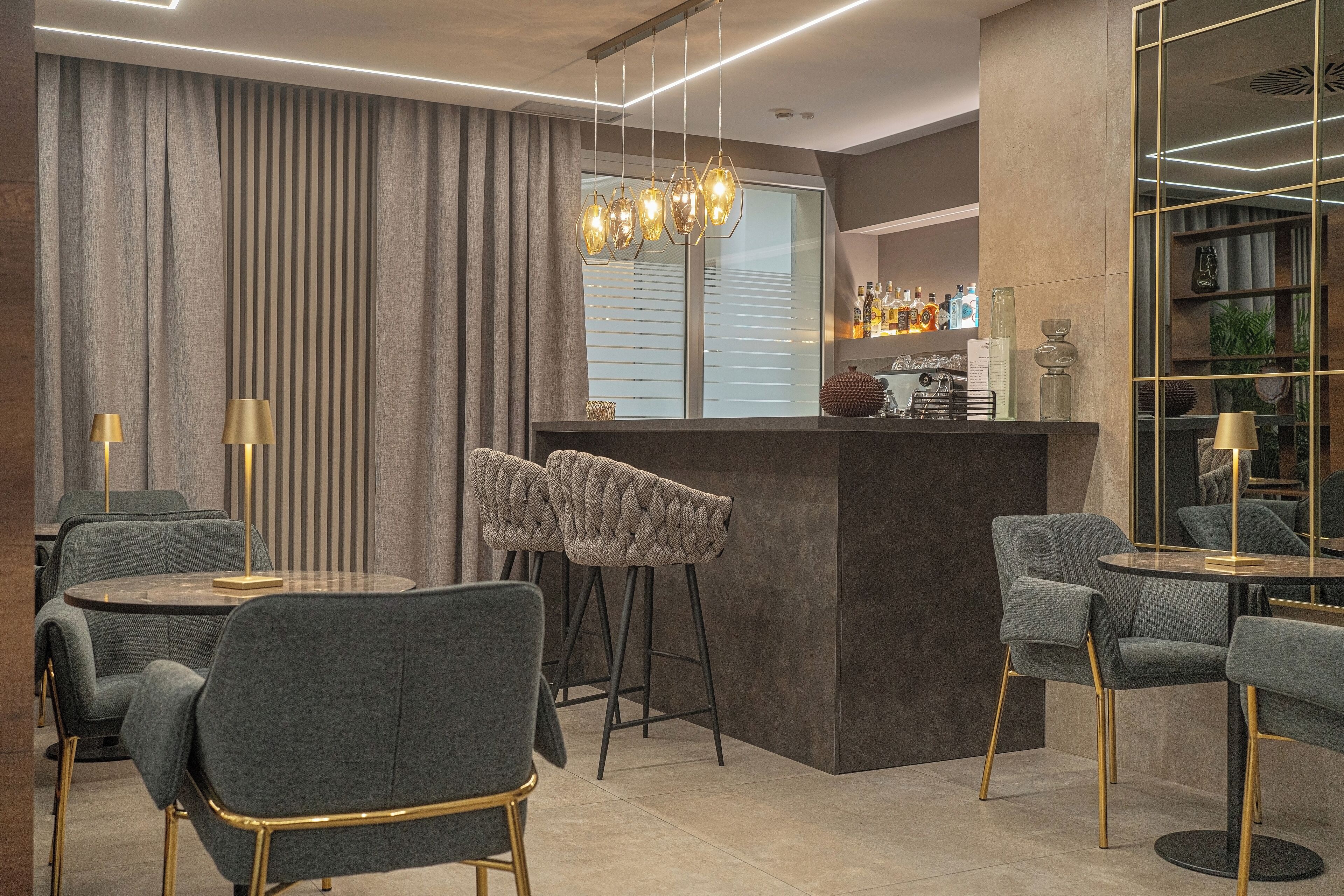 A modern bar area with bar stools, a round table, and a chandelier.