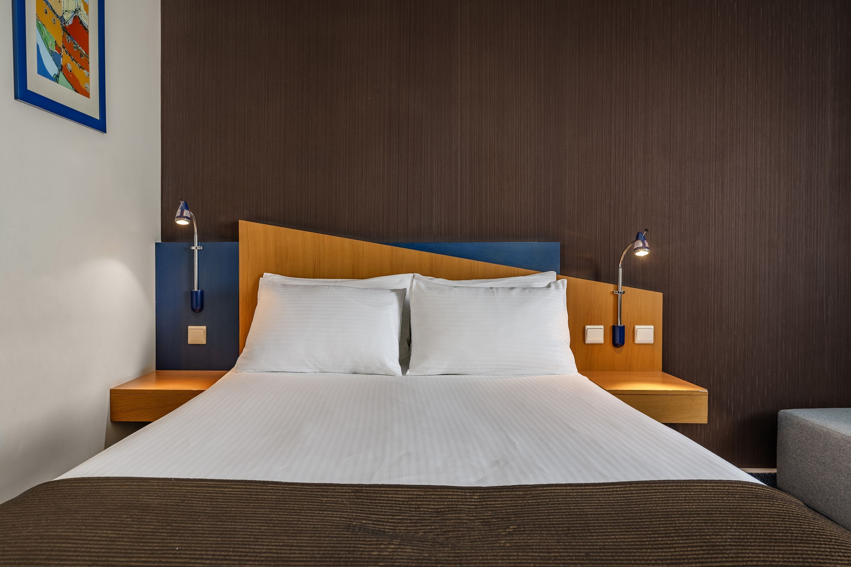 A hotel room with a large bed, two bedside tables, and a headboard.