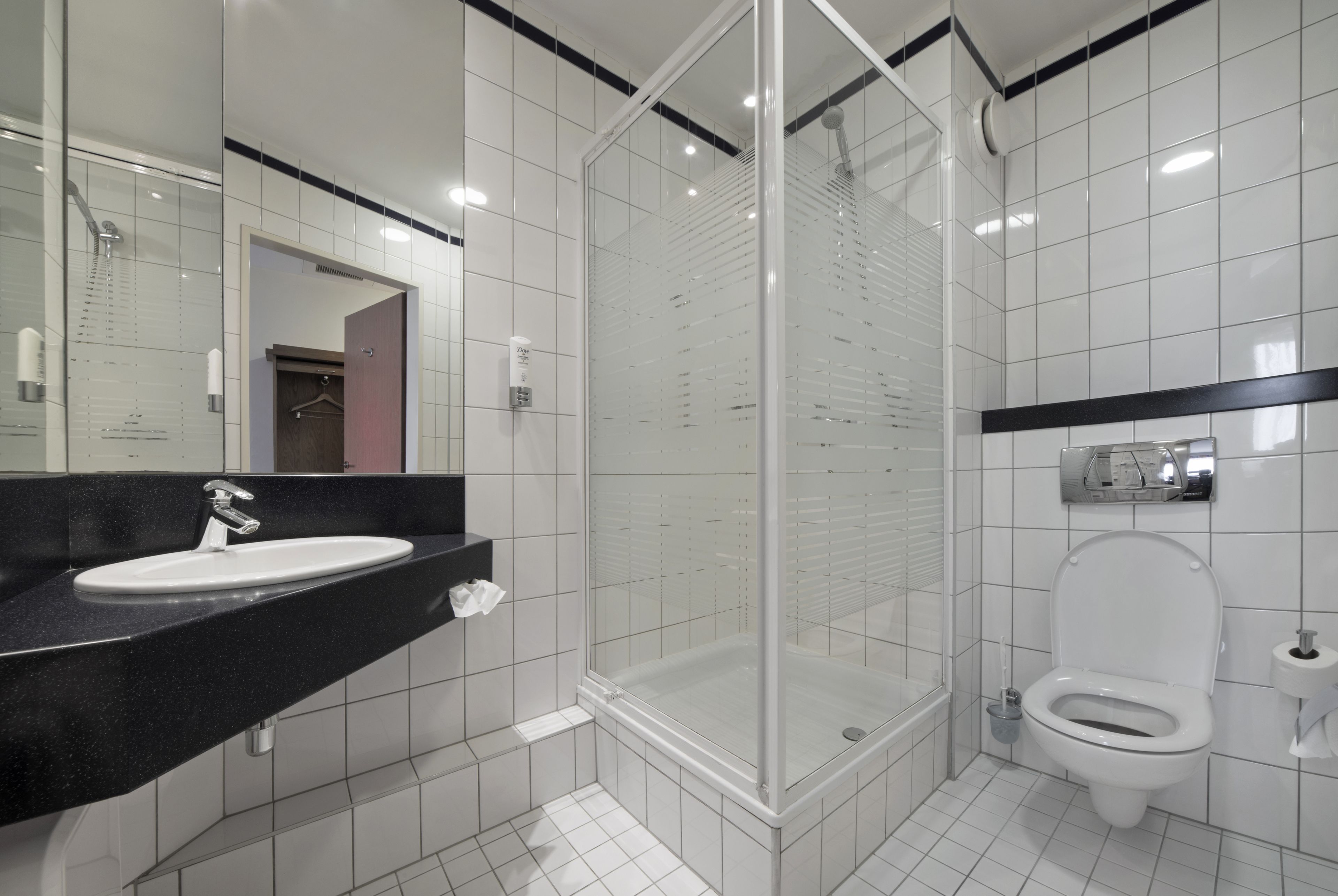 Un baño moderno con ducha de vidrio, lavamanos blanco y retrete.