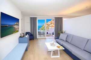 Una sala de estar moderna con un sofá, una mesa de centro, un banco y un televisor que muestra una vista panorámica.