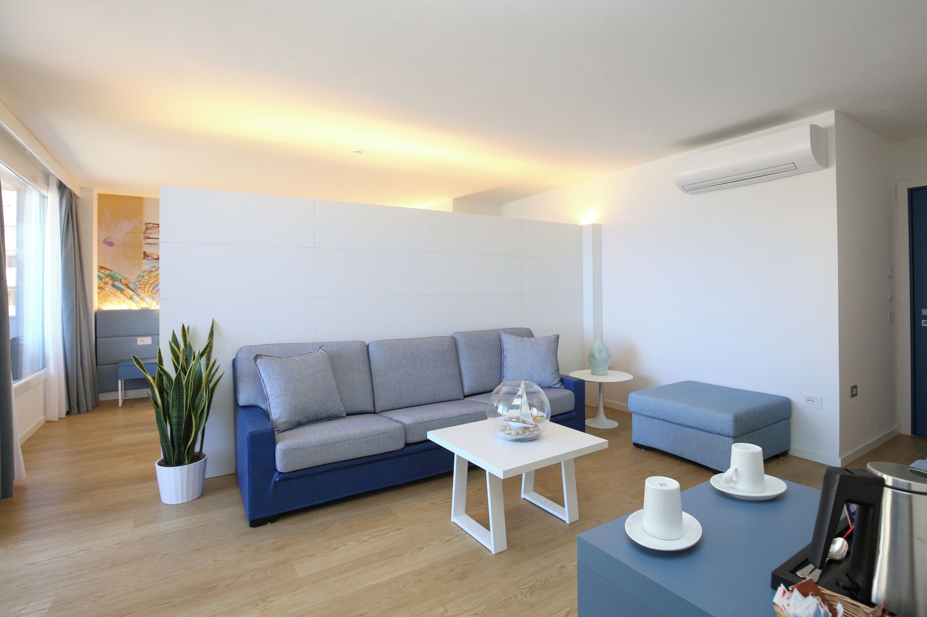 A modern living room with a sofa, a coffee table, a side table, and a potted plant.