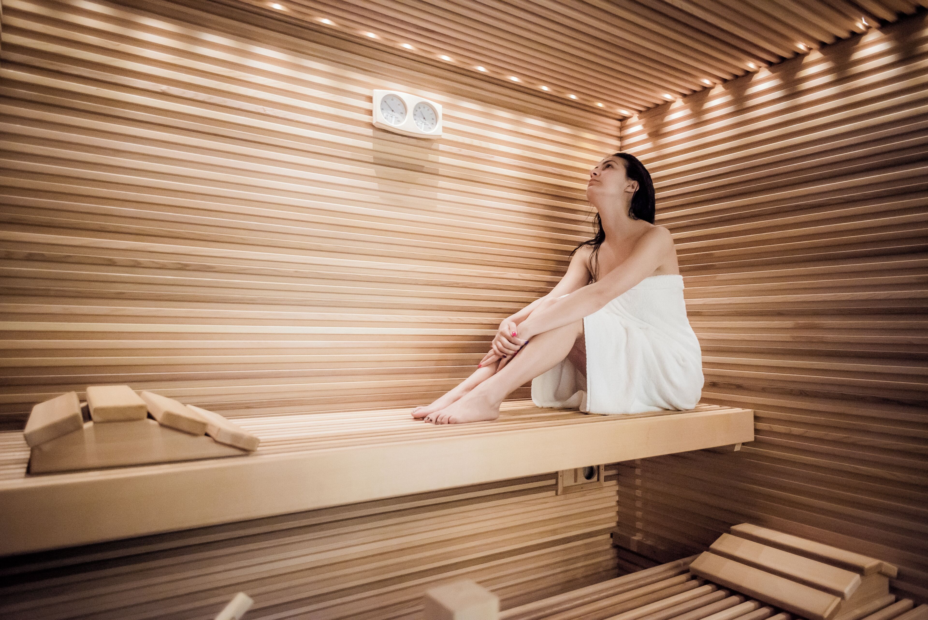 Una sauna con listones de madera, un banco y un reloj en la pared.