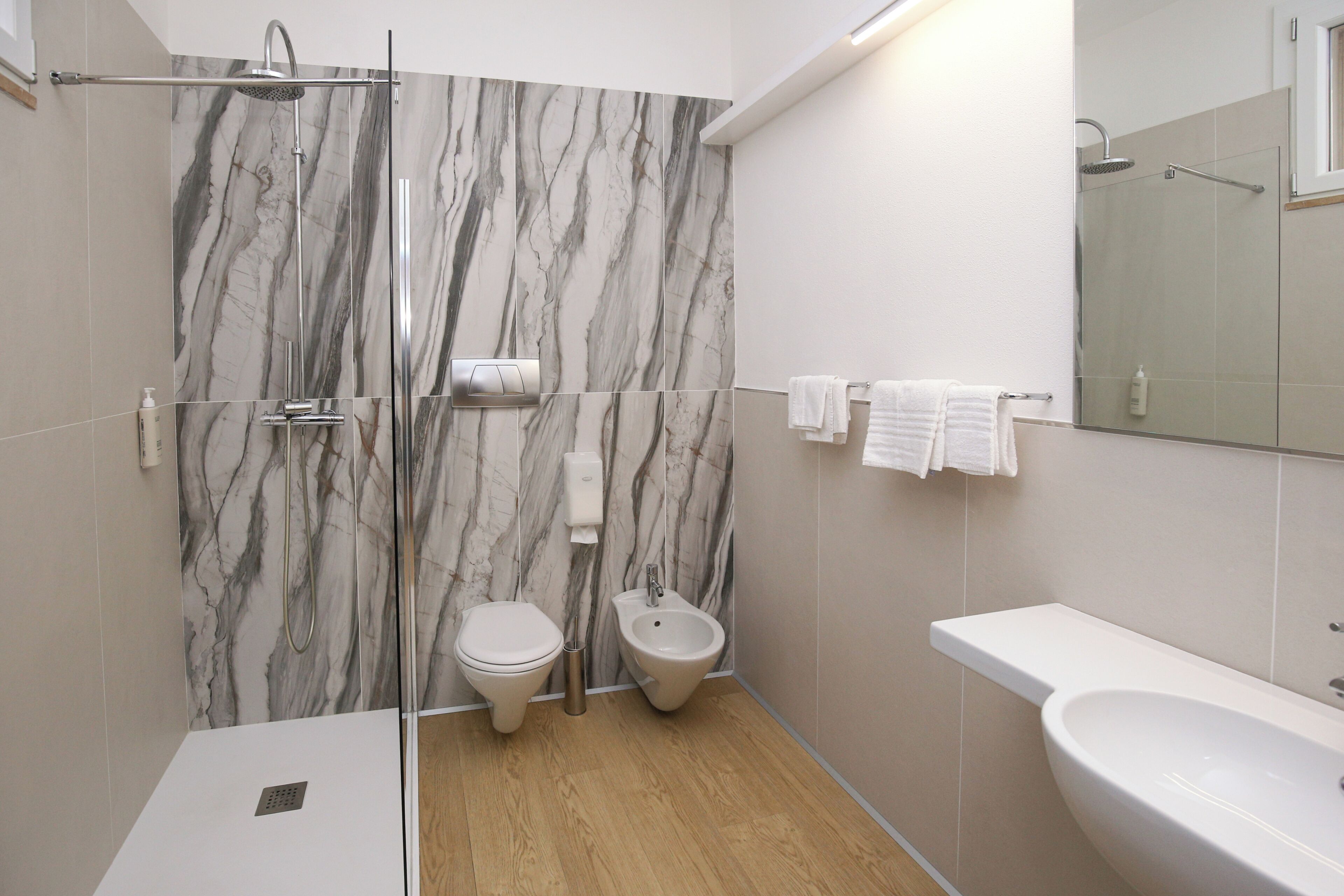 Ein modernes Badezimmer mit Dusche, Toilette, Bidet und Waschbecken.