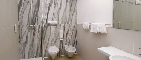 Un baño moderno con ducha, inodoro, bidé y lavamanos.