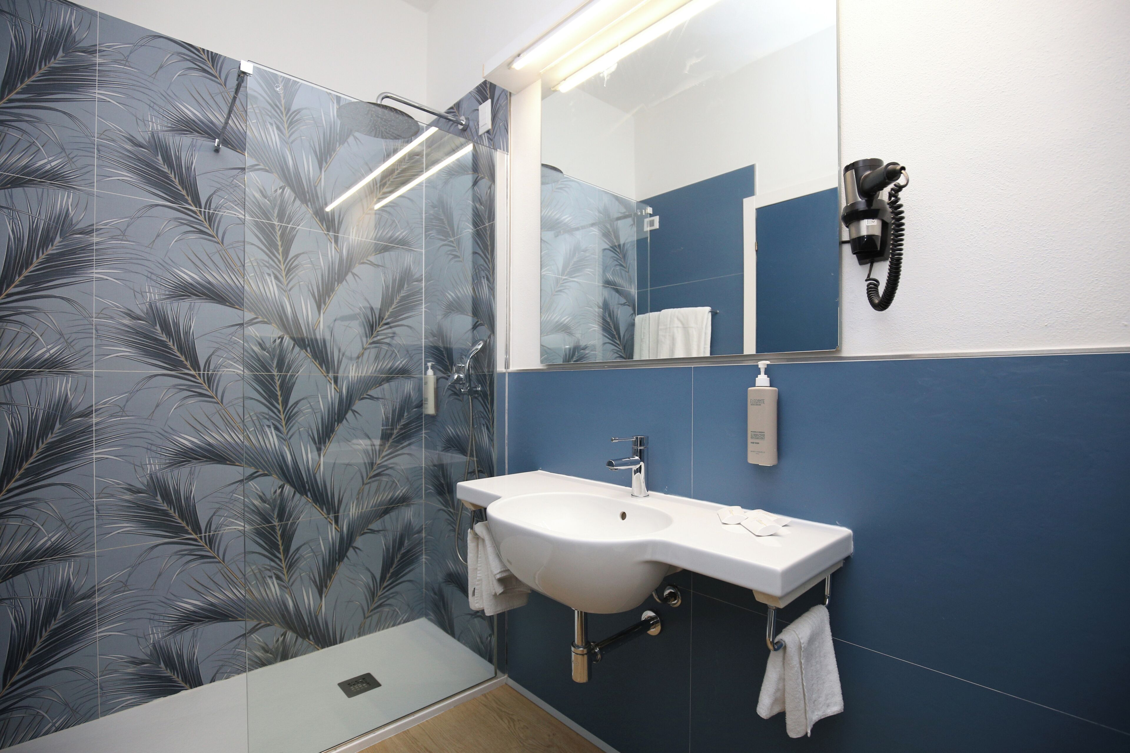 A bathroom with a shower, sink, and mirror.