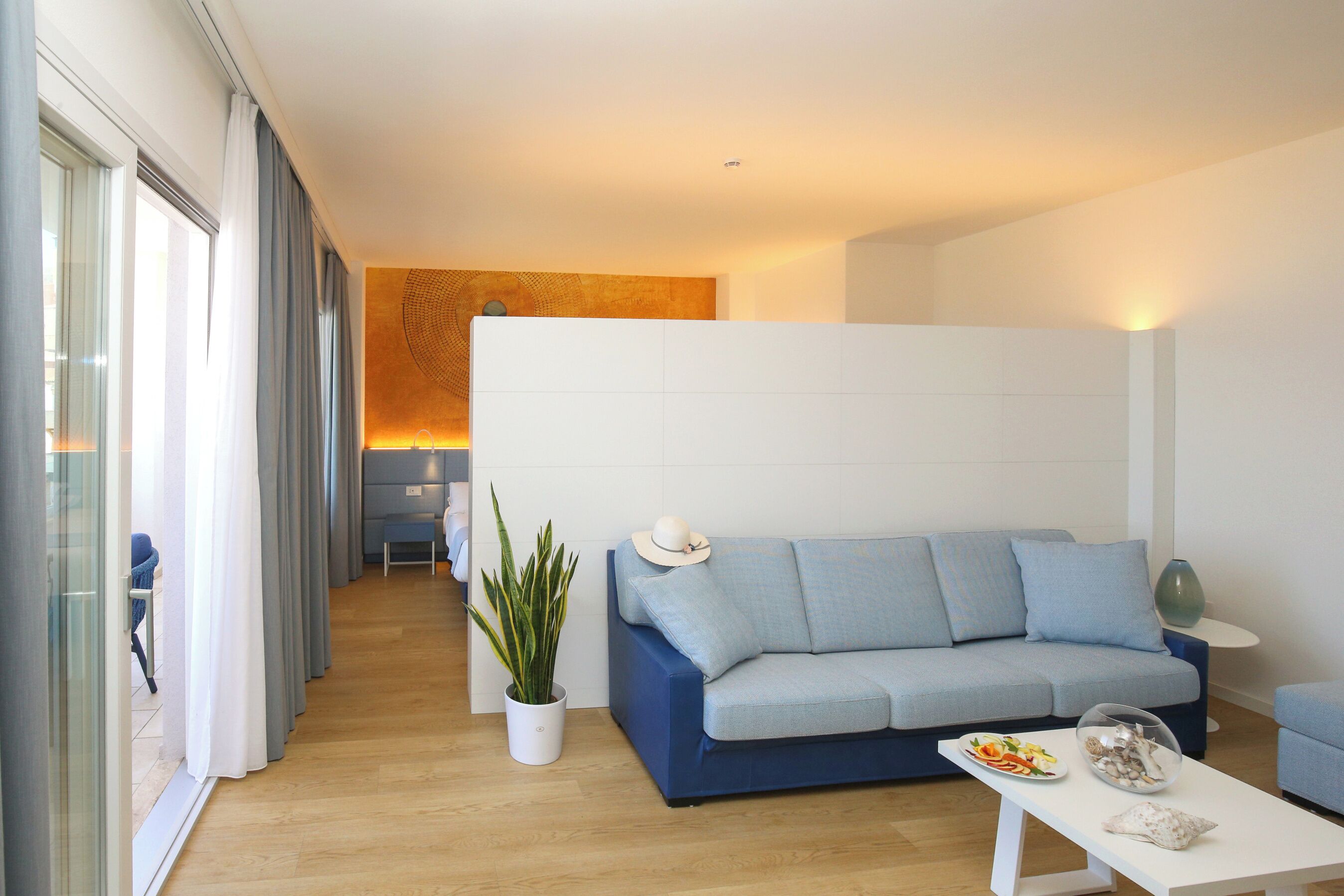 Una sala de estar moderna con un sofá azul, una mesa de centro blanca y una planta en maceta.