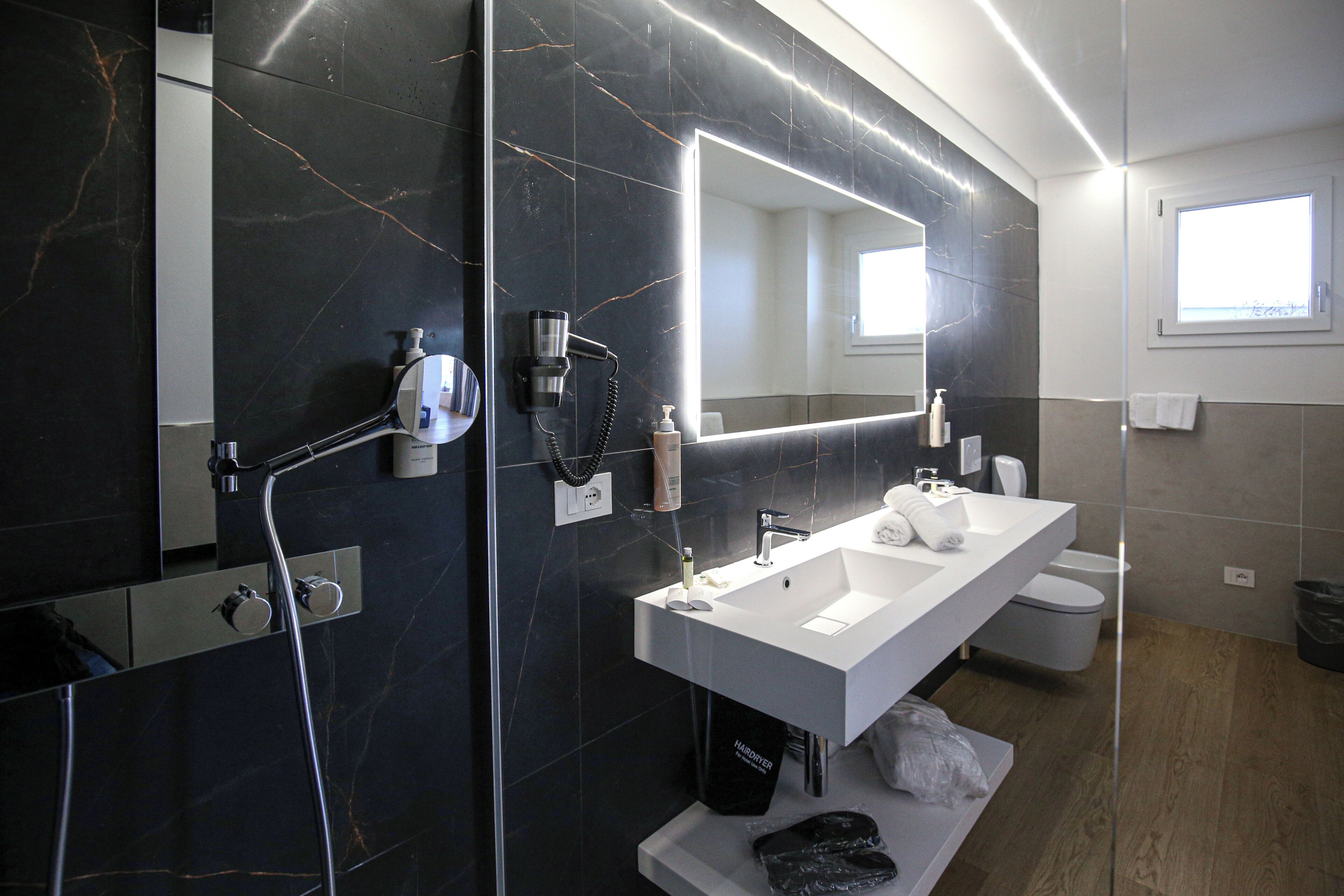 A modern bathroom with a large mirror, a white sink, and a shower area.