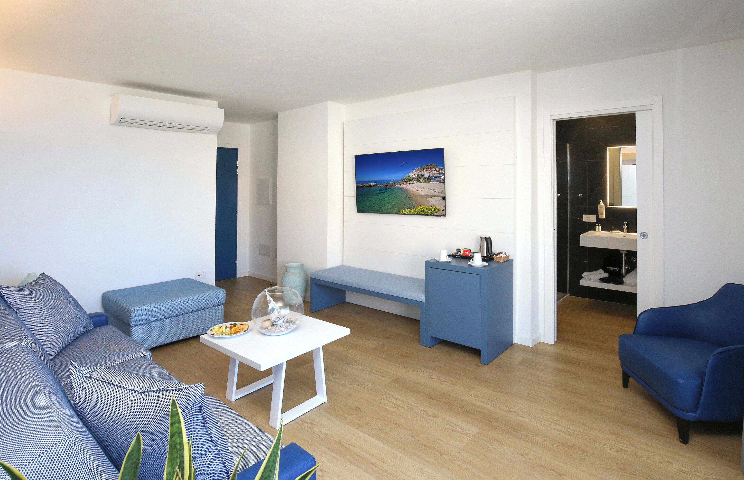 Een moderne woonkamer met een bank, een lange bank, een klein tafeltje en een schilderij van een kustlandschap.