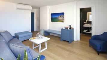 A modern living room with a sofa, a bench, a small table, and a painting of a coastal scene.