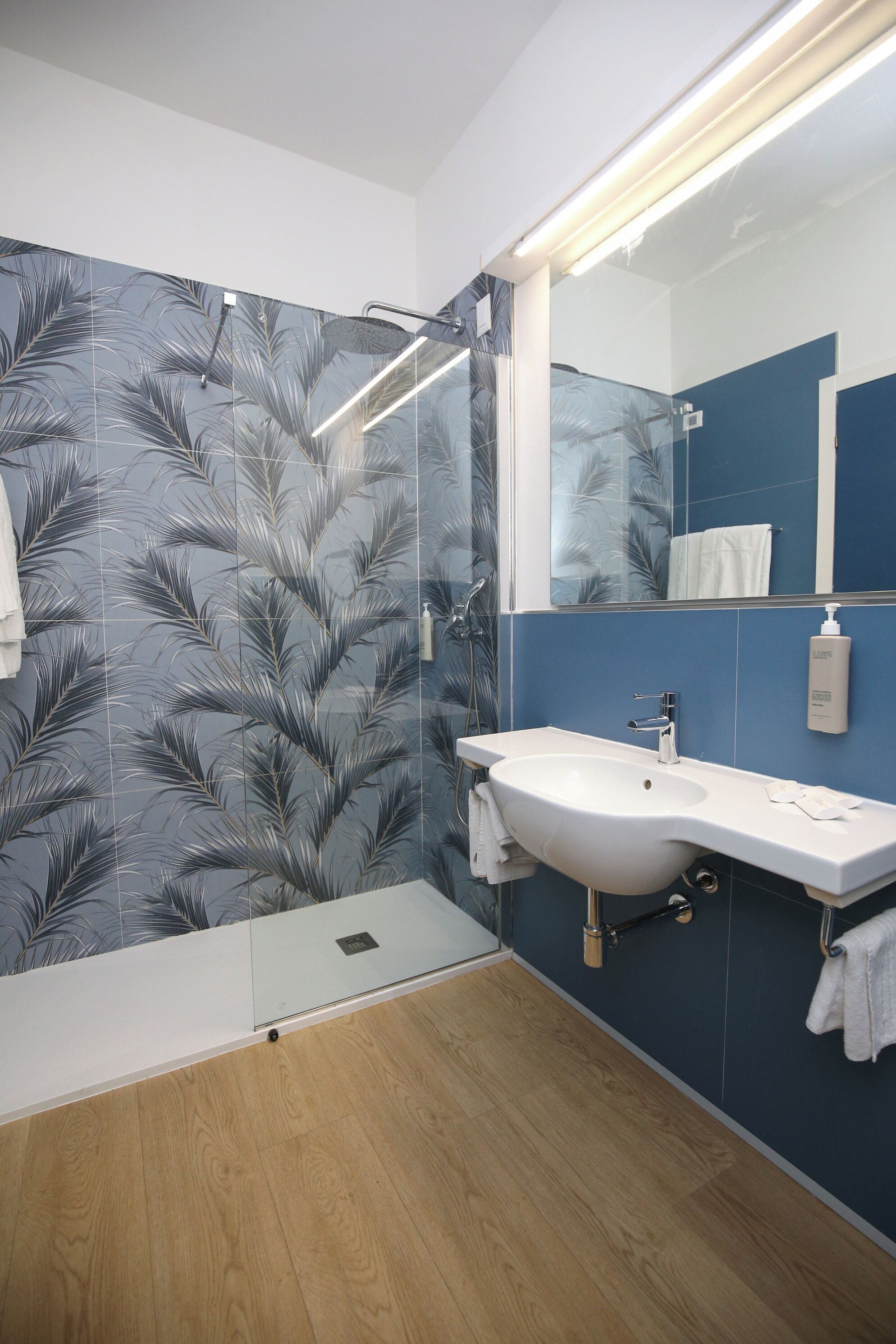A bathroom with a white sink, a mirror, and a shower with a glass door.