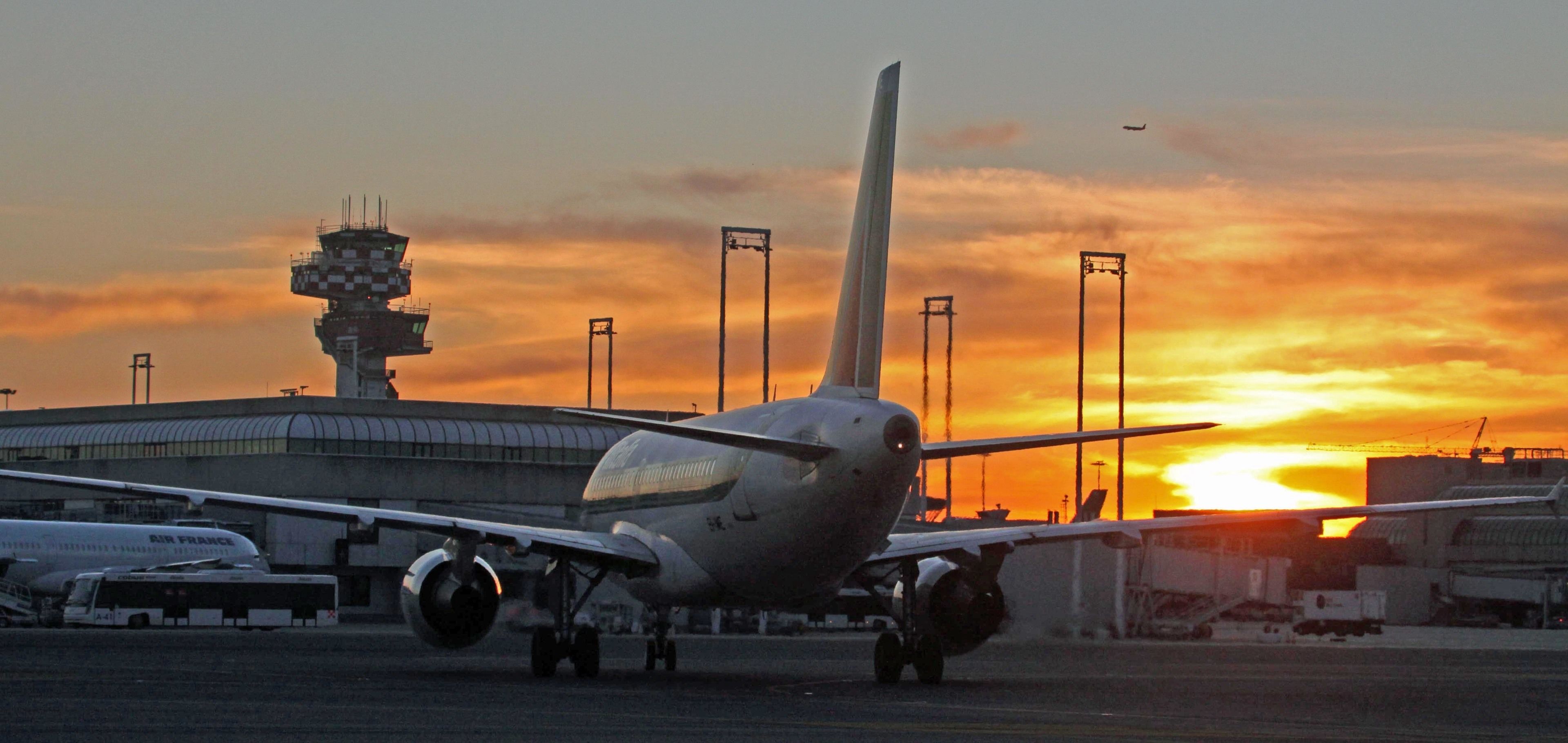 Un aeropuerto con un avión grande en la plataforma al atardecer.