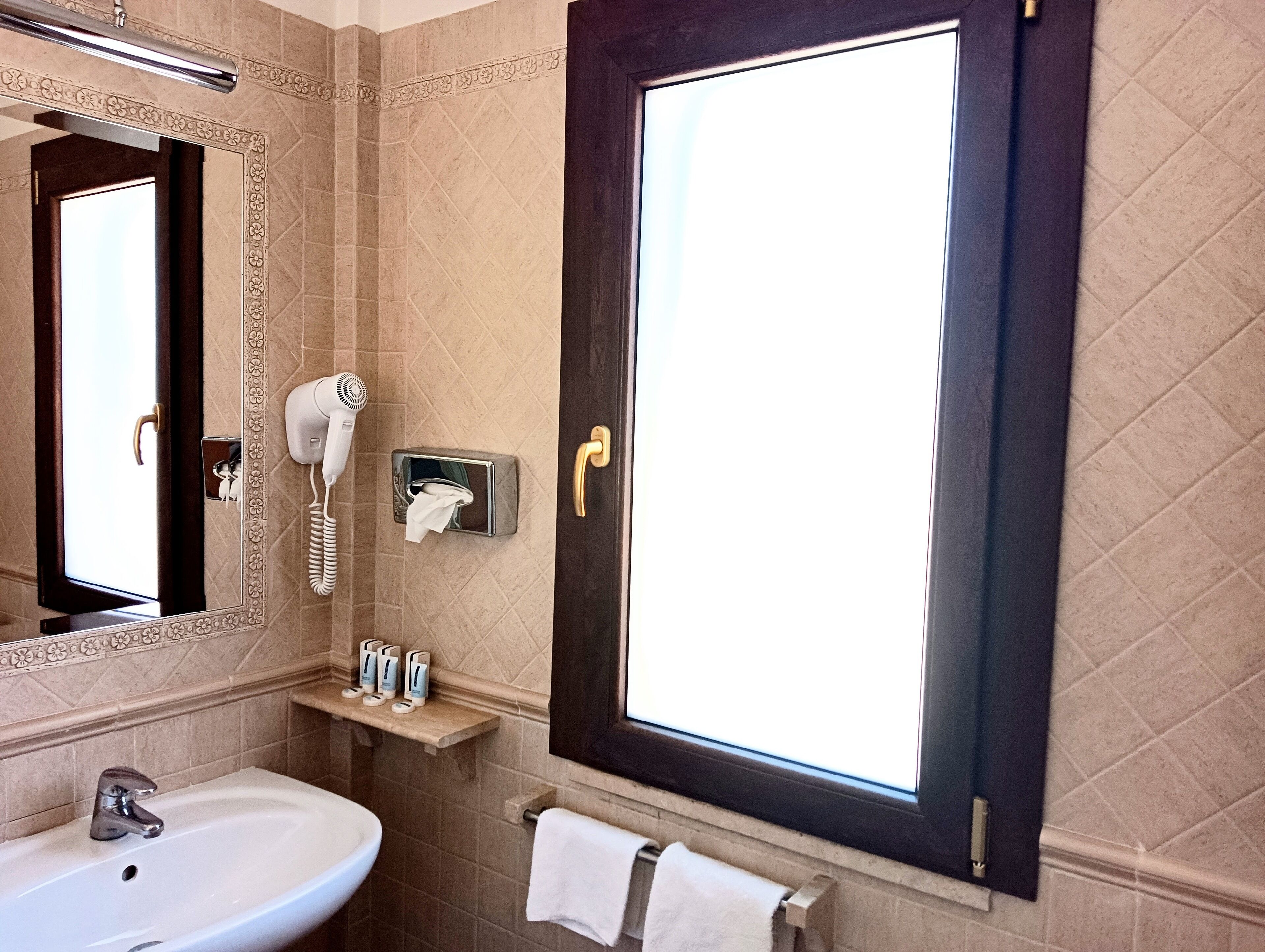 A bathroom with a large mirror, a sink, a hairdryer, and a towel rack.