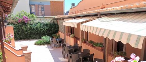 A courtyard with outdoor seating, potted plants, and a tiled pathway.