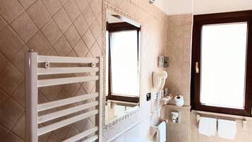 Un baño con un lavabo blanco, un espejo, un perchero para toallas y una ducha.