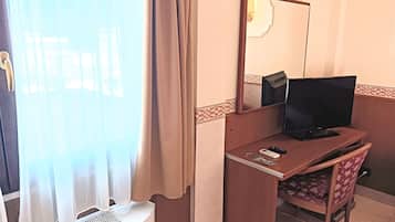 Une chambre d’hôtel équipée d’un bureau, d’une chaise, d’une télévision et d’un lit.