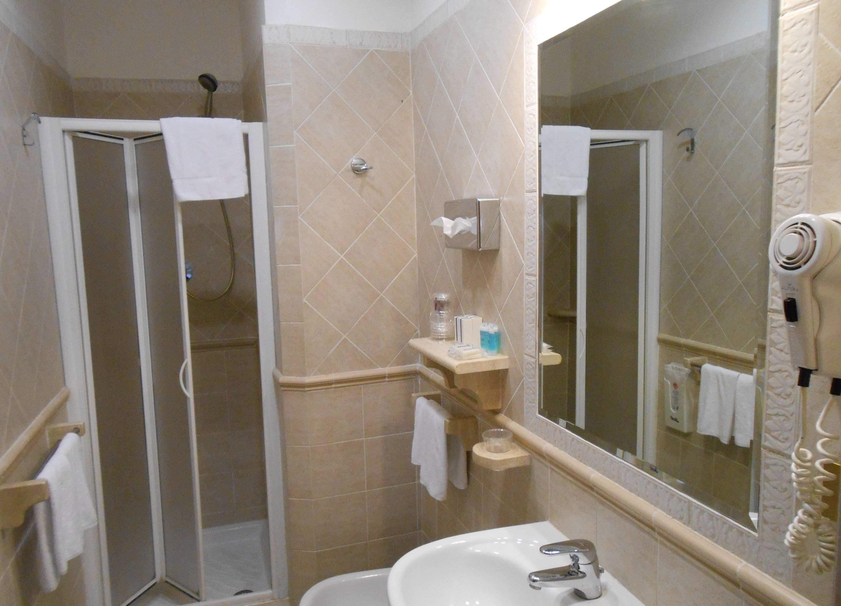 A bathroom with a shower, sink, and a large mirror.