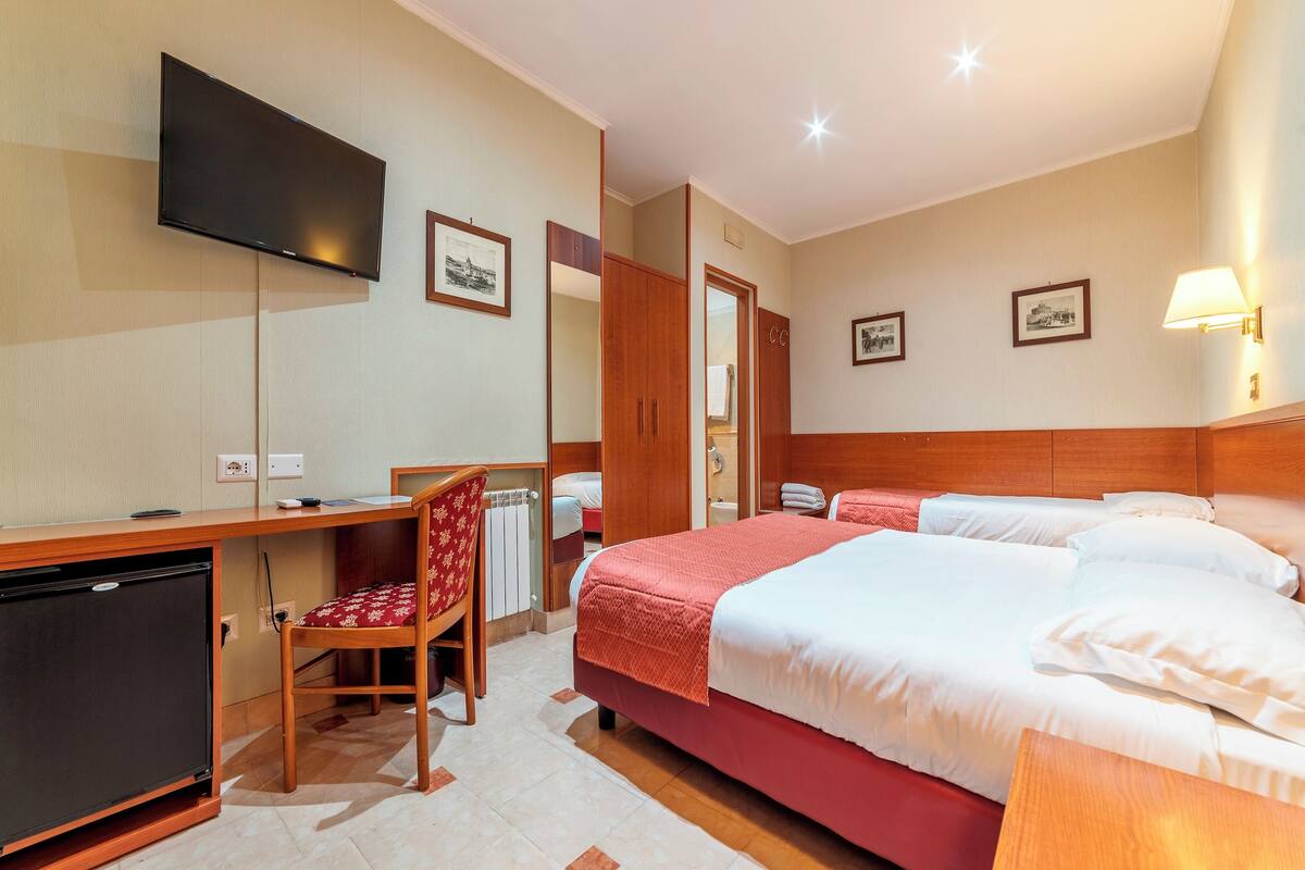 Een hotelkamer met een bed, bureau met stoel, televisie en kledingkast.
