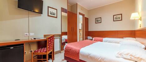 A hotel room with a bed, a desk with a chair, a television, and a wardrobe.
