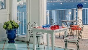 A balcony with a chessboard, chairs, and a potted plant. - Le Terrazze - Adults Only (Conca dei Marini)
