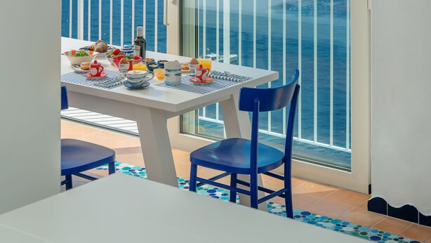 A balcony with a table set for breakfast, overlooking a coastal view with boats and cliffs. - Le Terrazze - Adults Only (Conca dei Marini)