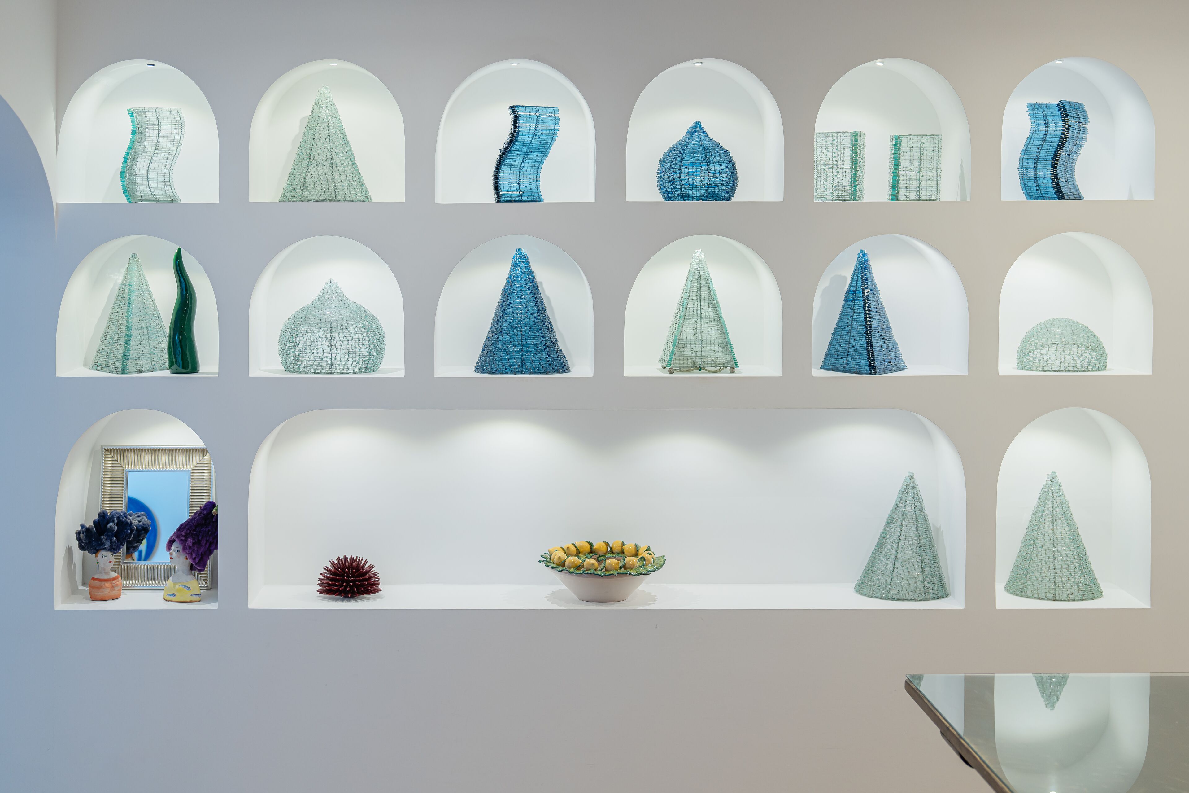 A series of geometric glass sculptures displayed in arched niches.