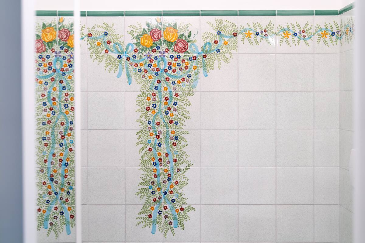 Casa de banho com parede revestida de azulejos com um padrão floral.