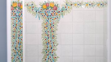 A bathroom with a tiled wall featuring a floral design.