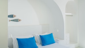 A hotel room with a bed, two blue pillows, a white bedside table, a white nightstand, a white lamp, and a wall-mounted shelf with two decorative fish. - Le Terrazze - Adults Only (Conca dei Marini)