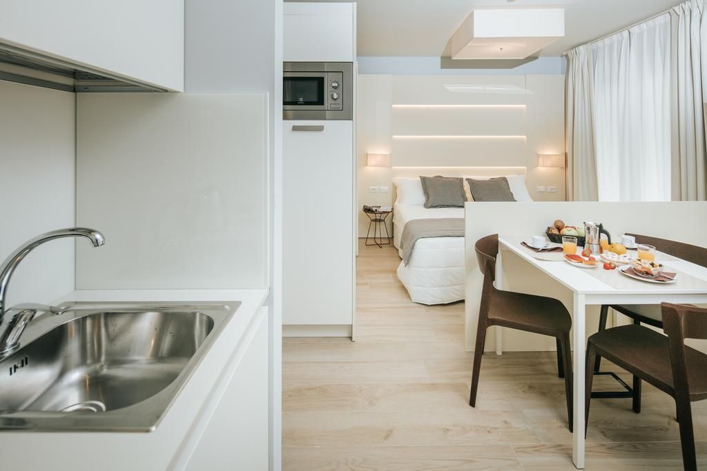 A modern kitchen with a built-in microwave, a stainless steel sink, and a dining area with a table set for breakfast.