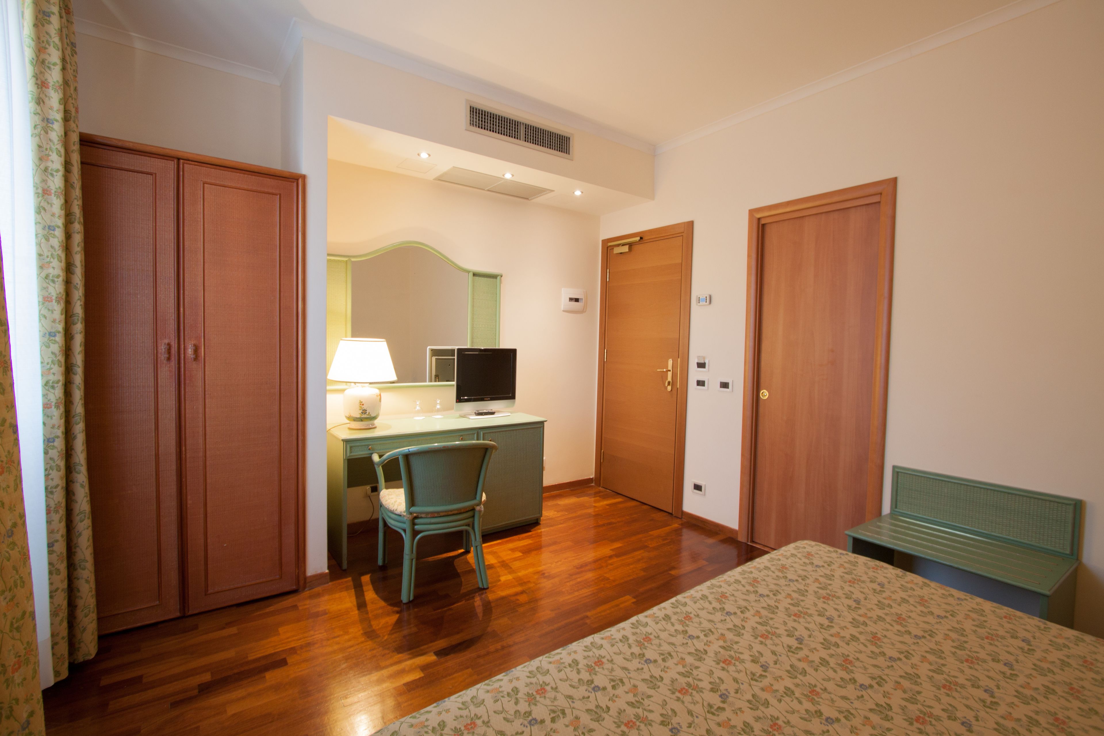 A bedroom with a bed, a desk with a chair, a television, and two wardrobes.