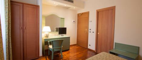 A bedroom with a bed, a desk with a chair, a television, and two wardrobes.