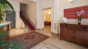 Un vestíbulo espacioso con una imponente escalera, una alfombra grande y una consola de madera.