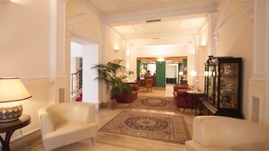 Un vestíbulo espacioso con una imponente escalera, una planta grande en maceta y un mueble de madera tradicional.
