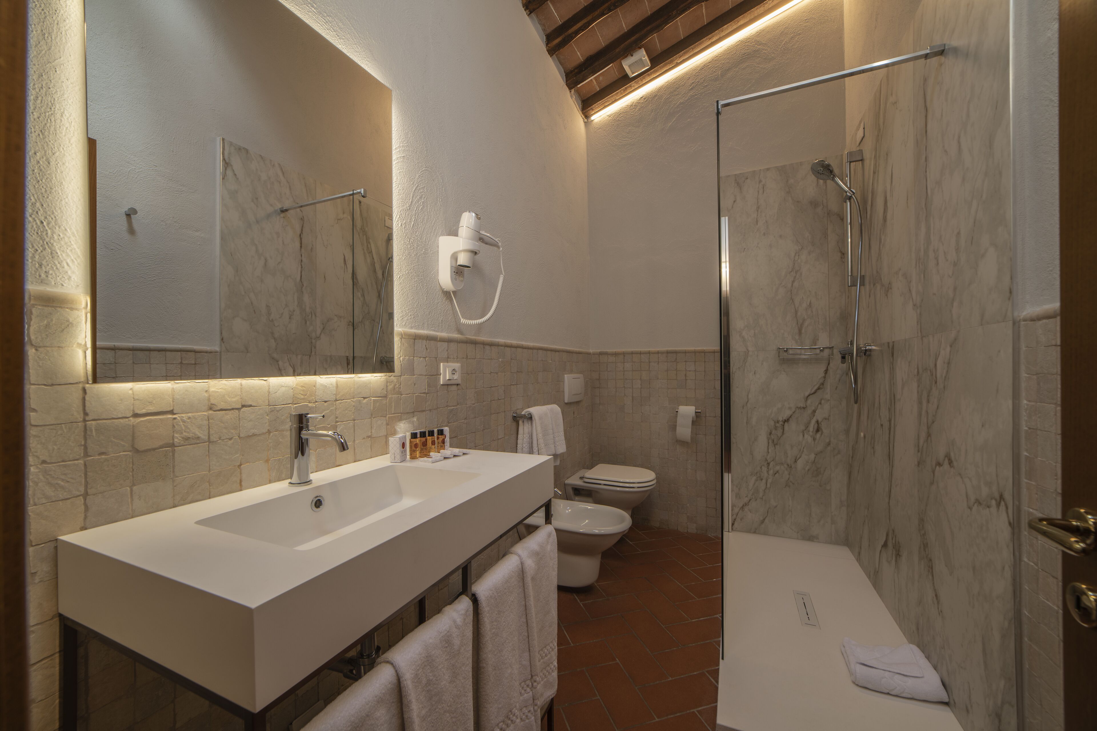Een moderne badkamer met een grote spiegel, een witte wastafel en een douche met glazen wanden.