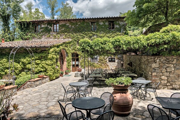 An outdoor patio with stone flooring, metal tables, and chairs.