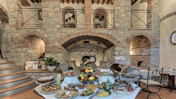 A stone-walled room with a table set for breakfast, featuring pastries, fruits, and a coffee station. - Ultimo Mulino Wellness Country Hotel (Gaiole in Chianti)