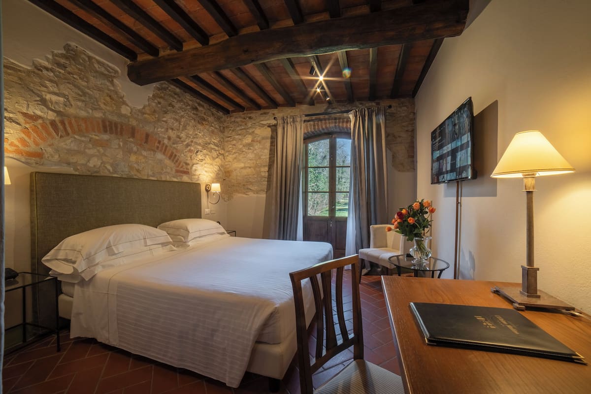 Un dormitorio con una cama, un escritorio, una silla, una lámpara y un cuadro en la pared.