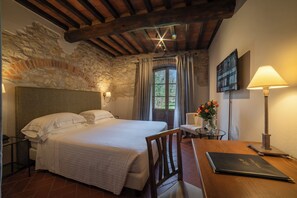 A bedroom with a bed, a desk, a chair, a lamp, and a painting on the wall.
