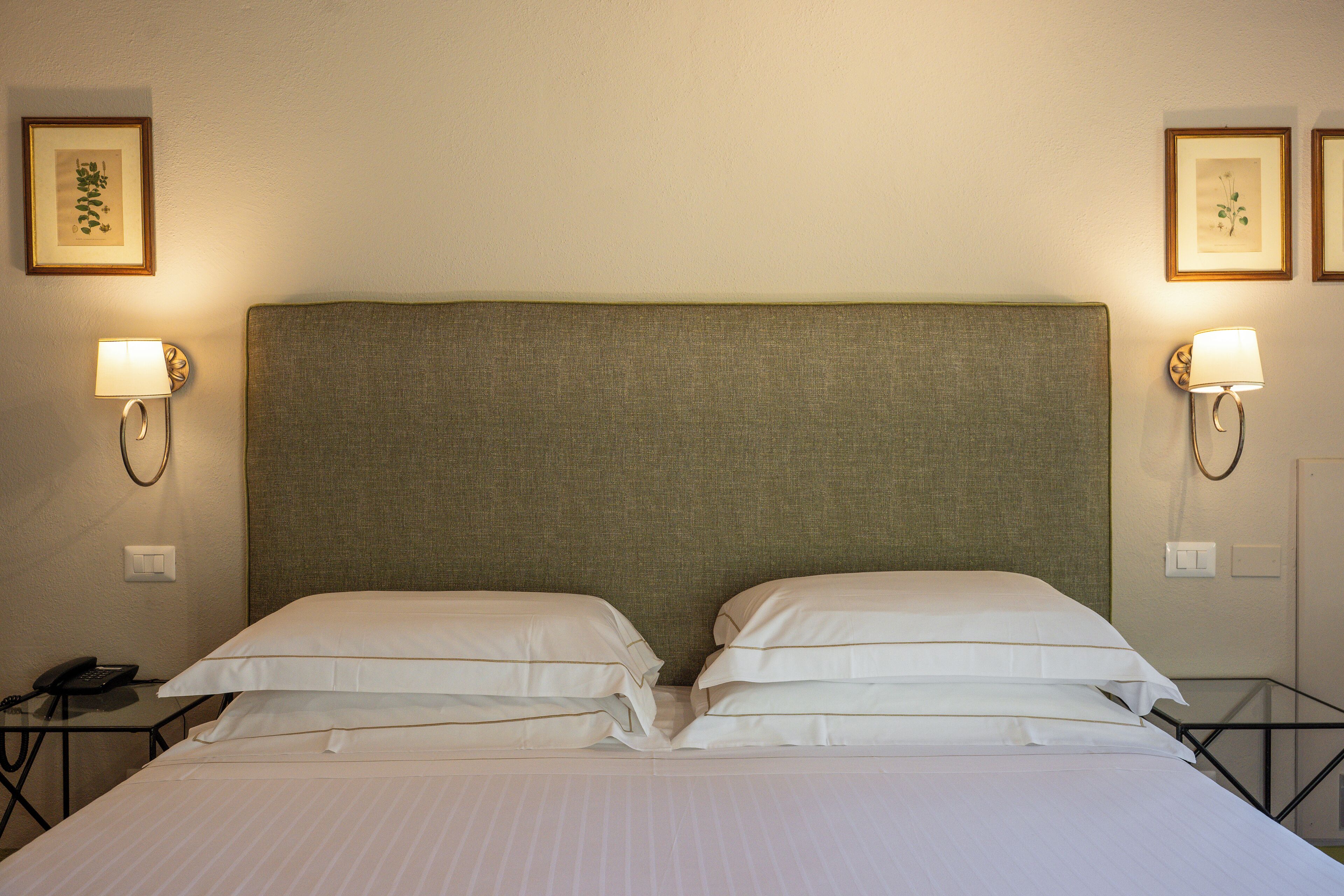 Una habitación de hotel con una cama grande, dos lámparas de noche y un teléfono sobre una mesita.