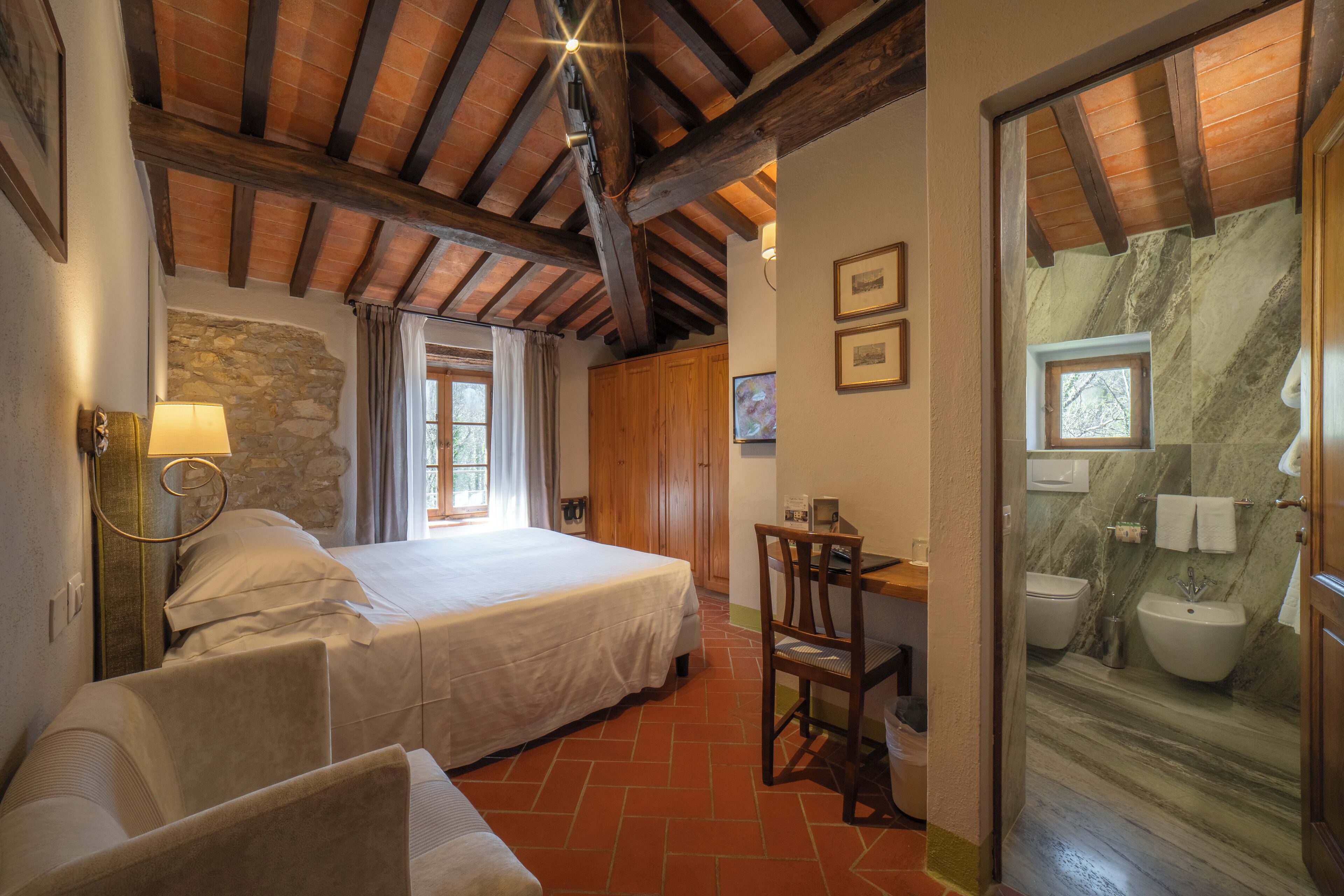 Un dormitorio con cama, escritorio y baño con pared de mármol.