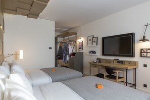 Una habitación de hotel moderna con dos camas, un escritorio, un televisor y un armario.