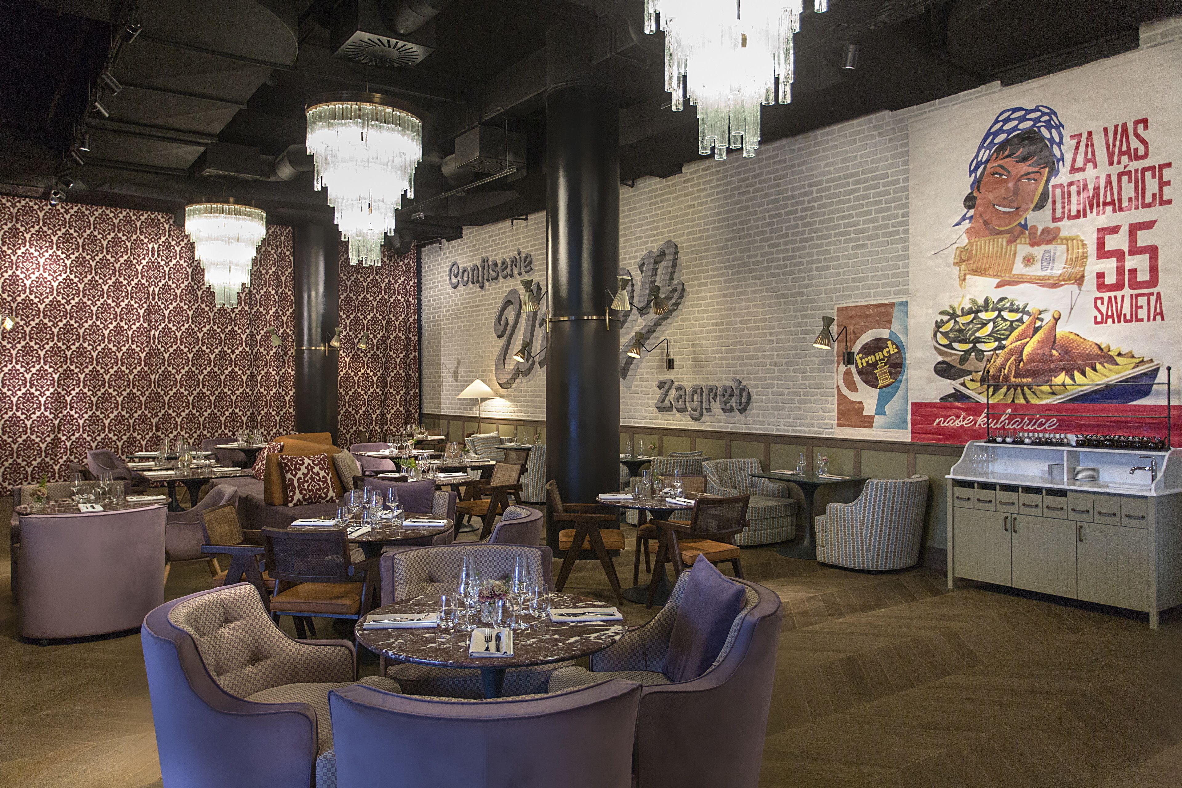 A restaurant interior with round tables, chairs, and a large mural on the wall.