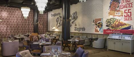 A restaurant interior with round tables, chairs, and a large mural on the wall.