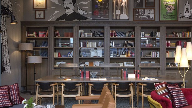 Una biblioteca con estanterías, una mesa de comedor, sillas y un sofá.