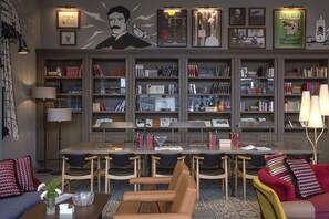 Una biblioteca amb prestatges, una taula de menjador, cadires i un sofà.