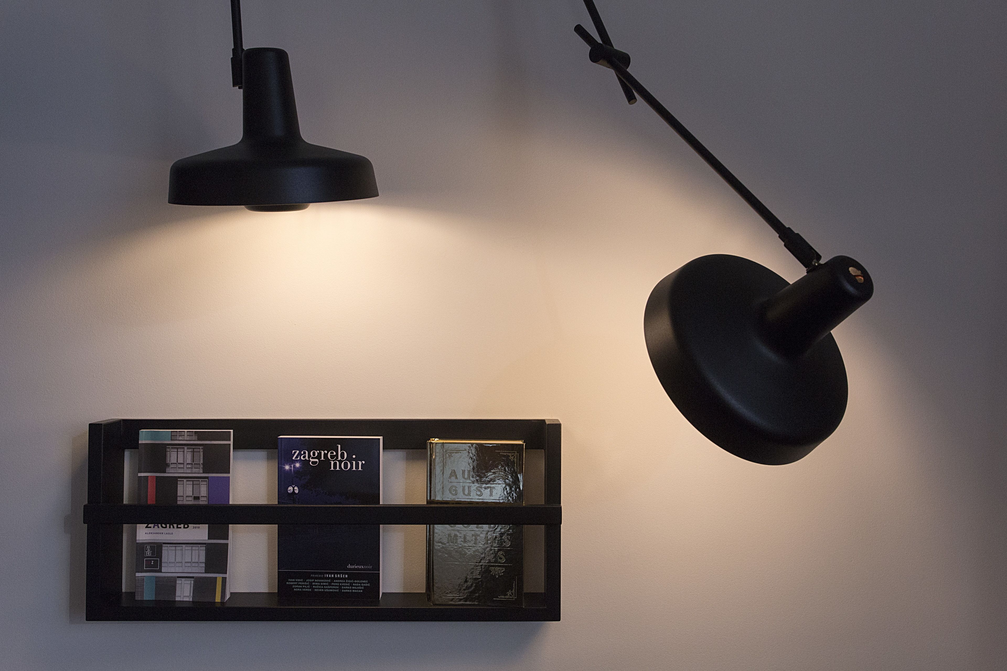 A wall-mounted shelf with books and a black pendant light.