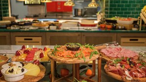 Una mesa de buffet con diversos alimentos, incluyendo quesos, frutas y carnes.