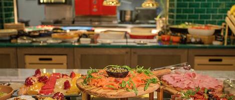 Una mesa de buffet con diversos alimentos, incluyendo quesos, frutas y carnes.