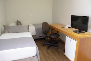 A hotel room with a bed, a desk with a computer, a chair, and a small fridge. - Travel Inn Flats Santo Andre (Santo André)